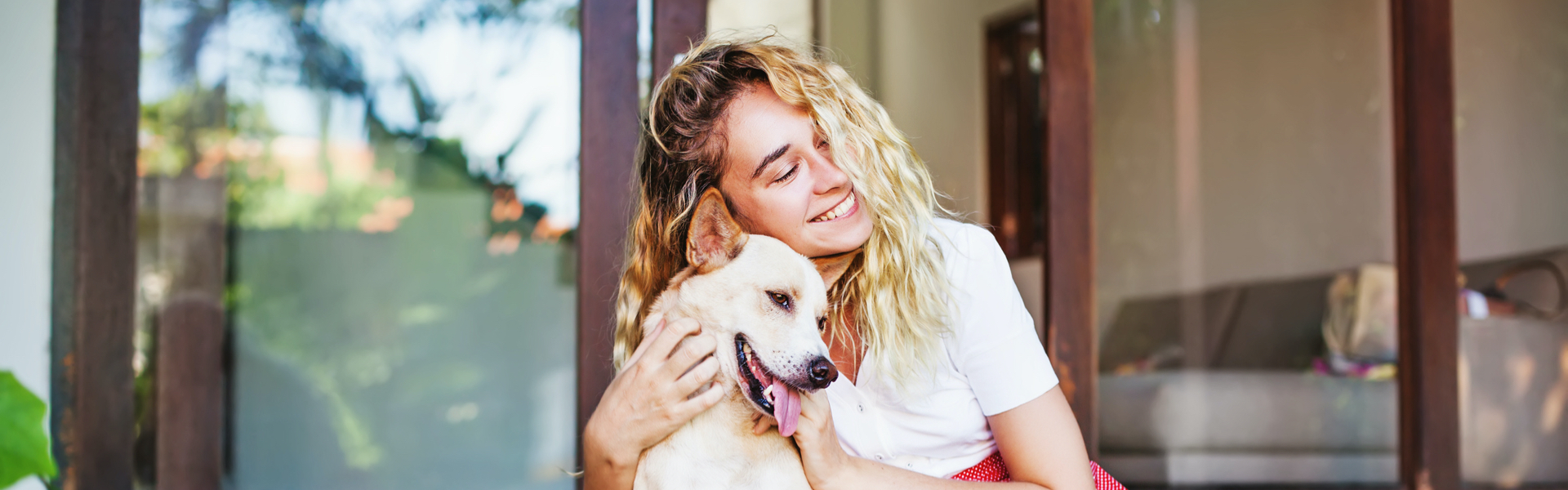 A woman smiles while cuddling her dog.