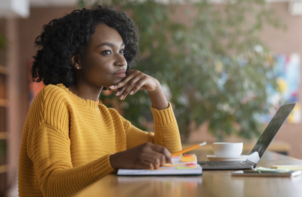 Woman sitting at a desk in front of a laptop. 