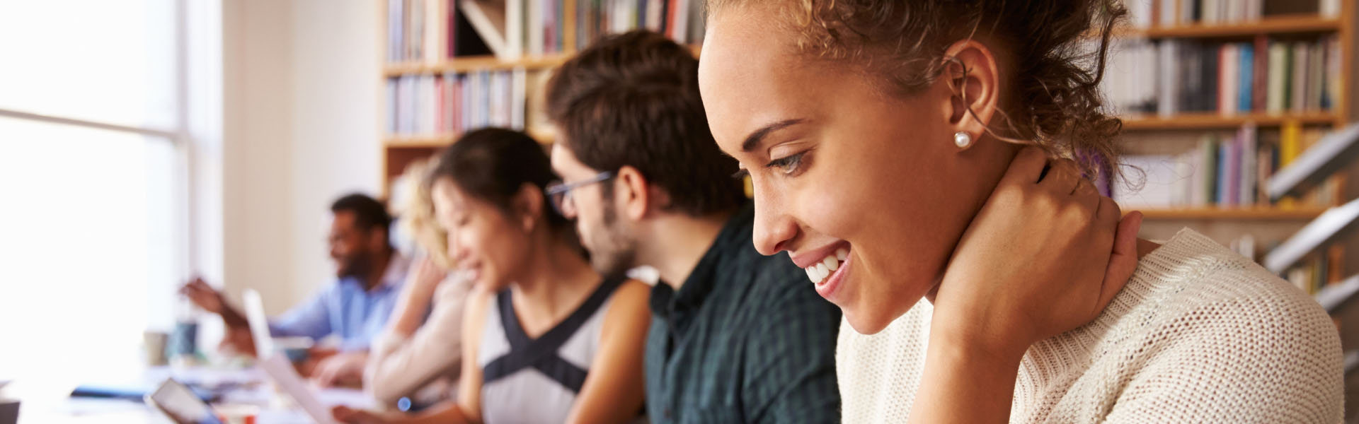 A group of young adults are in a library.	