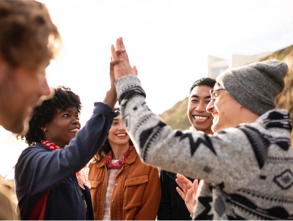 A young man and woman are giving each other a high-five while other members of the group excitedly smile at them.