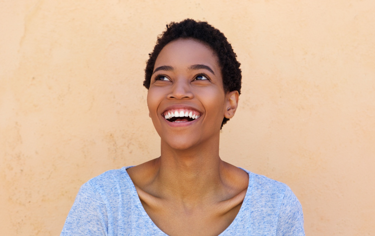 A woman is smiling and looking up and to her right.