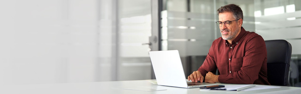 A man is sitting a desk and working on a laptop.