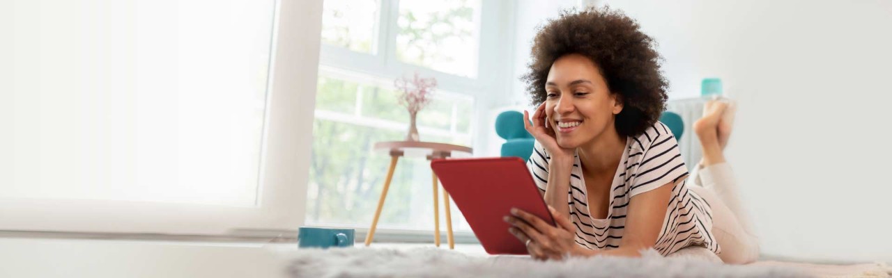 A woman in a striped shirt looks at a tablet