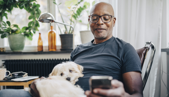 Man relaxing with his dog on his mobile phone
