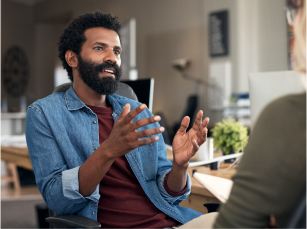  A young man is talking and gesticulating with open palms to someone off screen
