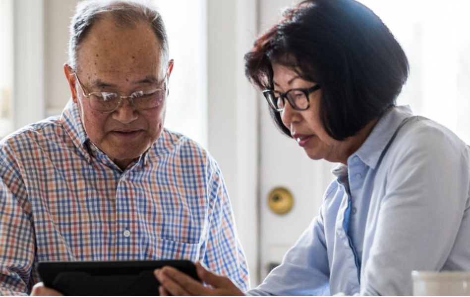 Two people sharing a tablet are researching information.