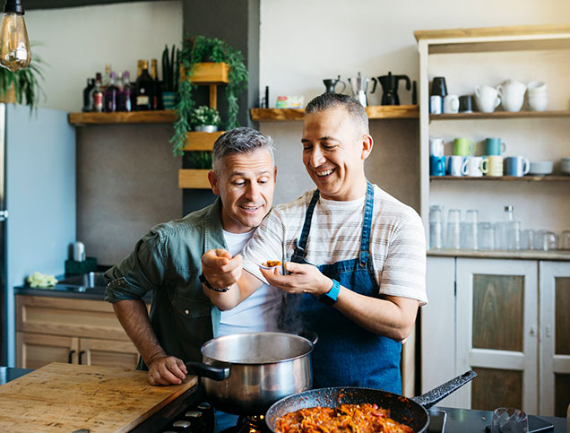 A couple in their kitchen cooking and laughing.