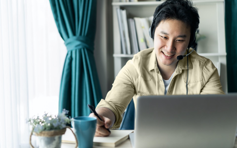 A man attends a video call from a laptop in his home office.