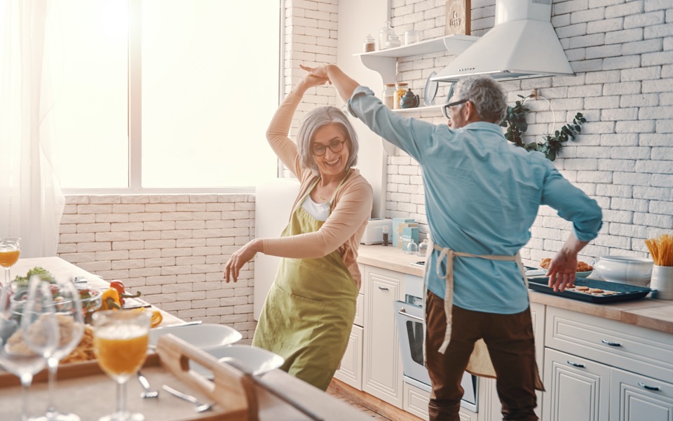 An older couple is dancing in their kitchen after learning about spousal IRAs.