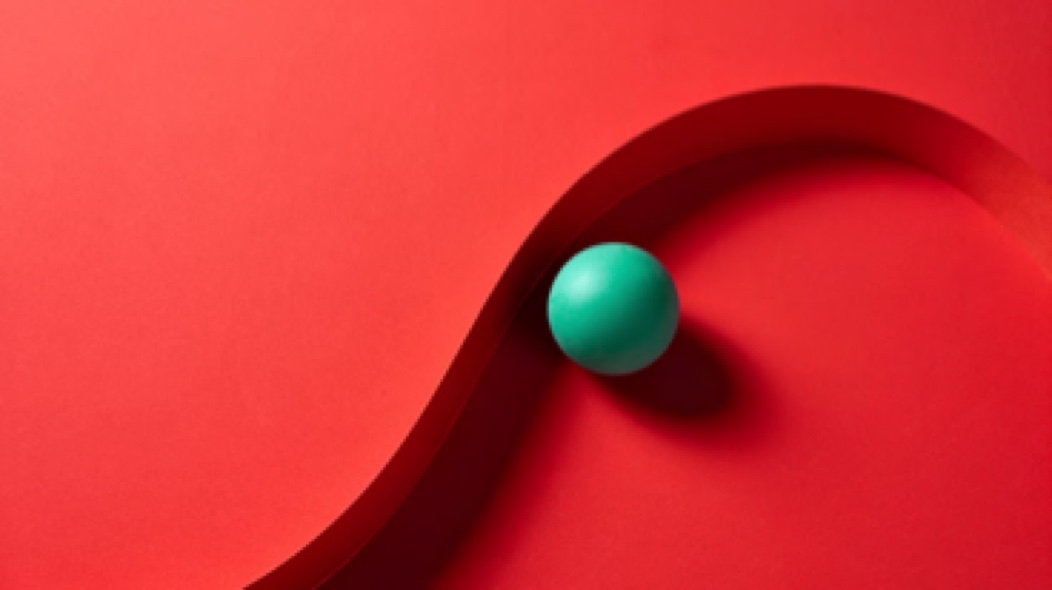 A green ball is resting on a red background.