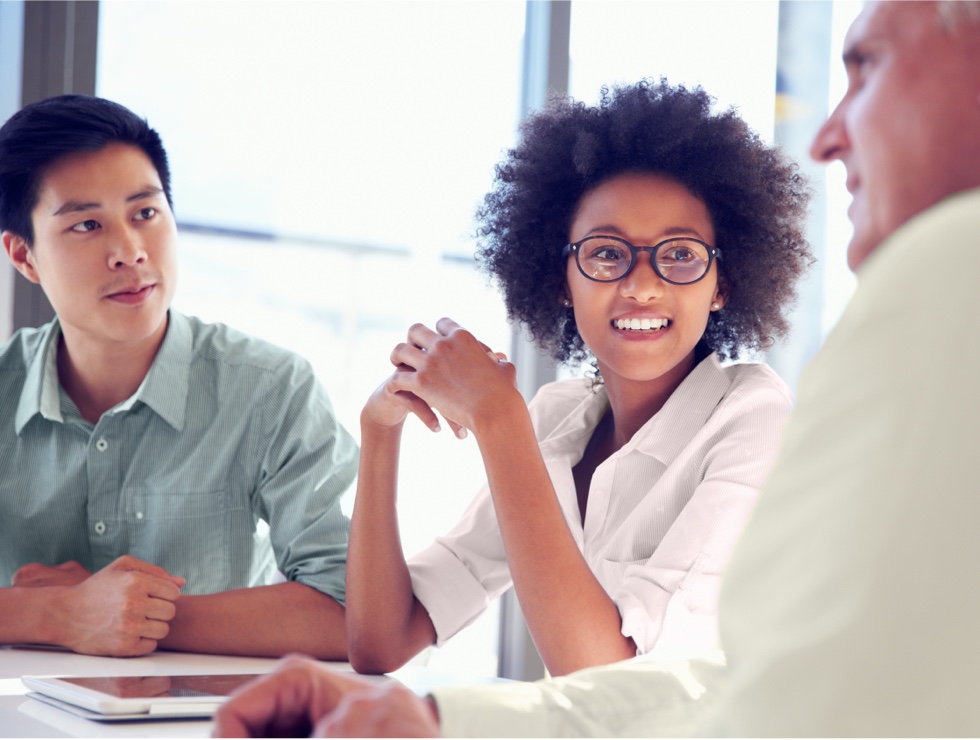 Three business professionals are collaborating at a table in front of a window.