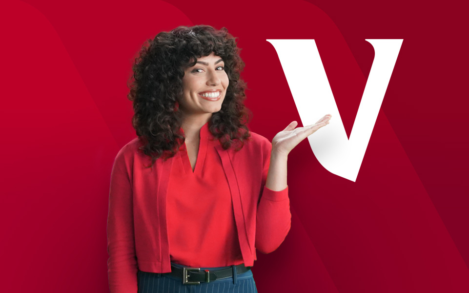 Woman in red shirt gesturing towards white Vanguard V on red background.