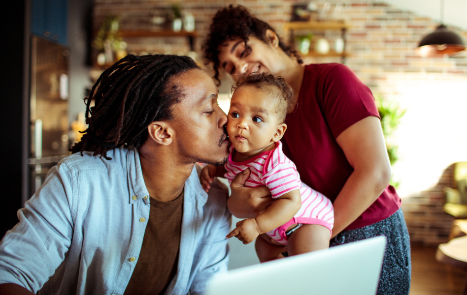 A woman brings her baby over so her partner can take a break from working and give them a kiss.  