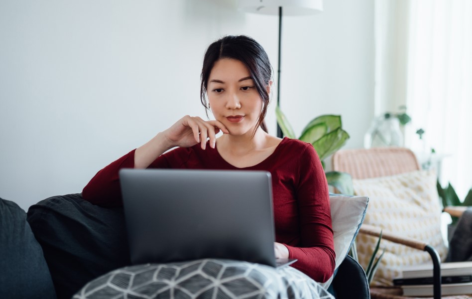 Seated woman on living room sofa looking at laptop 