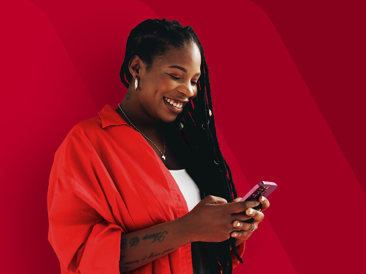 A woman holding a mobile phone against a red patterned background.