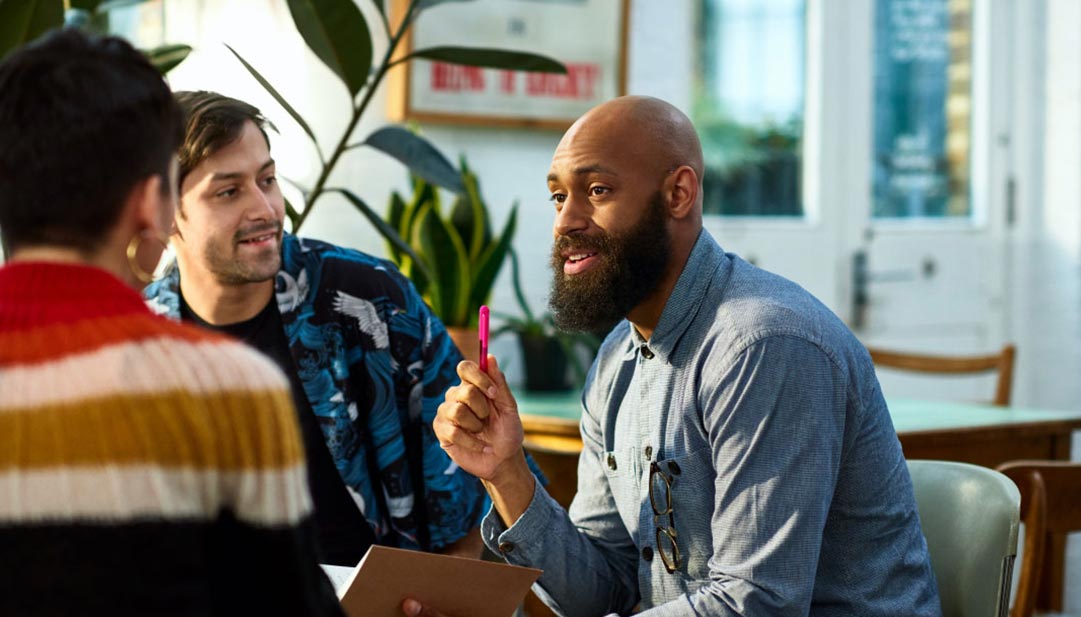 Three people talking in a creative workspace.