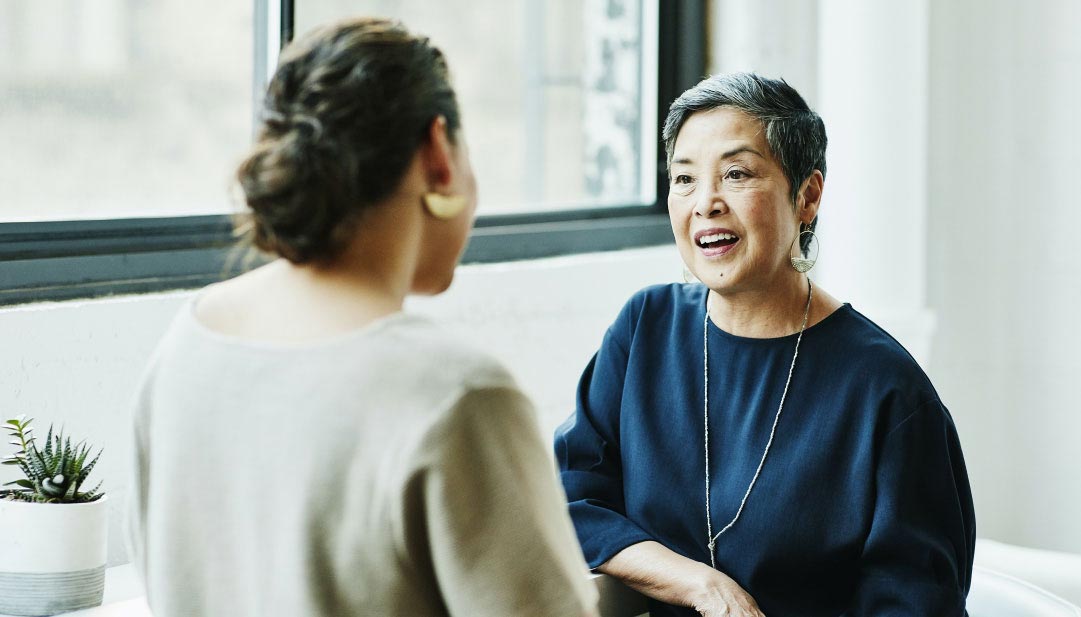 Two women talking in a white office. 