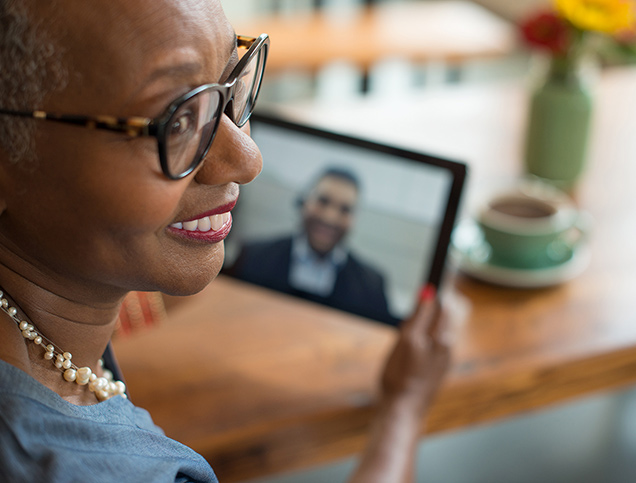 A woman smiles as she speaks with her financial advisor on a video call.