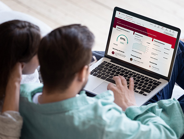 A couple sit side-by-side viewing their account dashboard on a laptop.