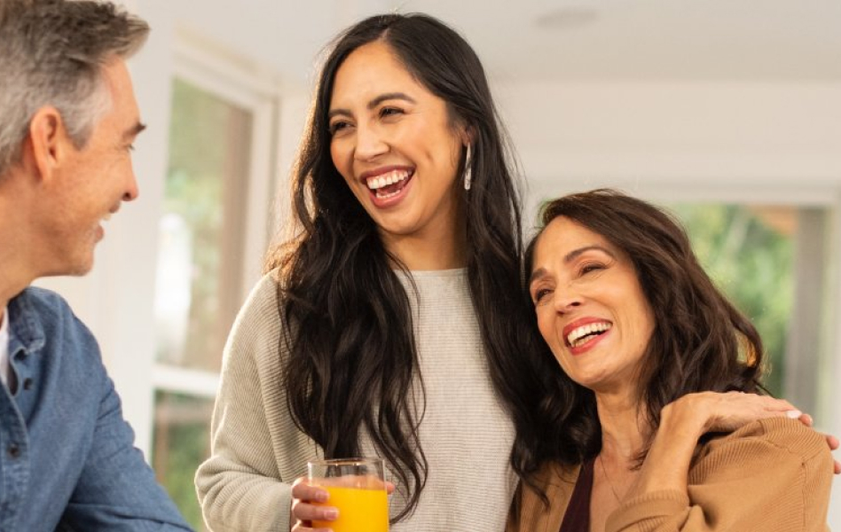 A mother, father, and daughter are brightly smiling and gathered around a table for breakfast.