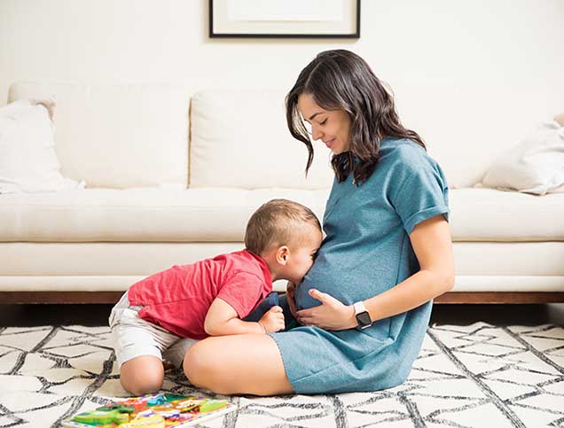 Little boy kissing his mom’s pregnant belly. 
