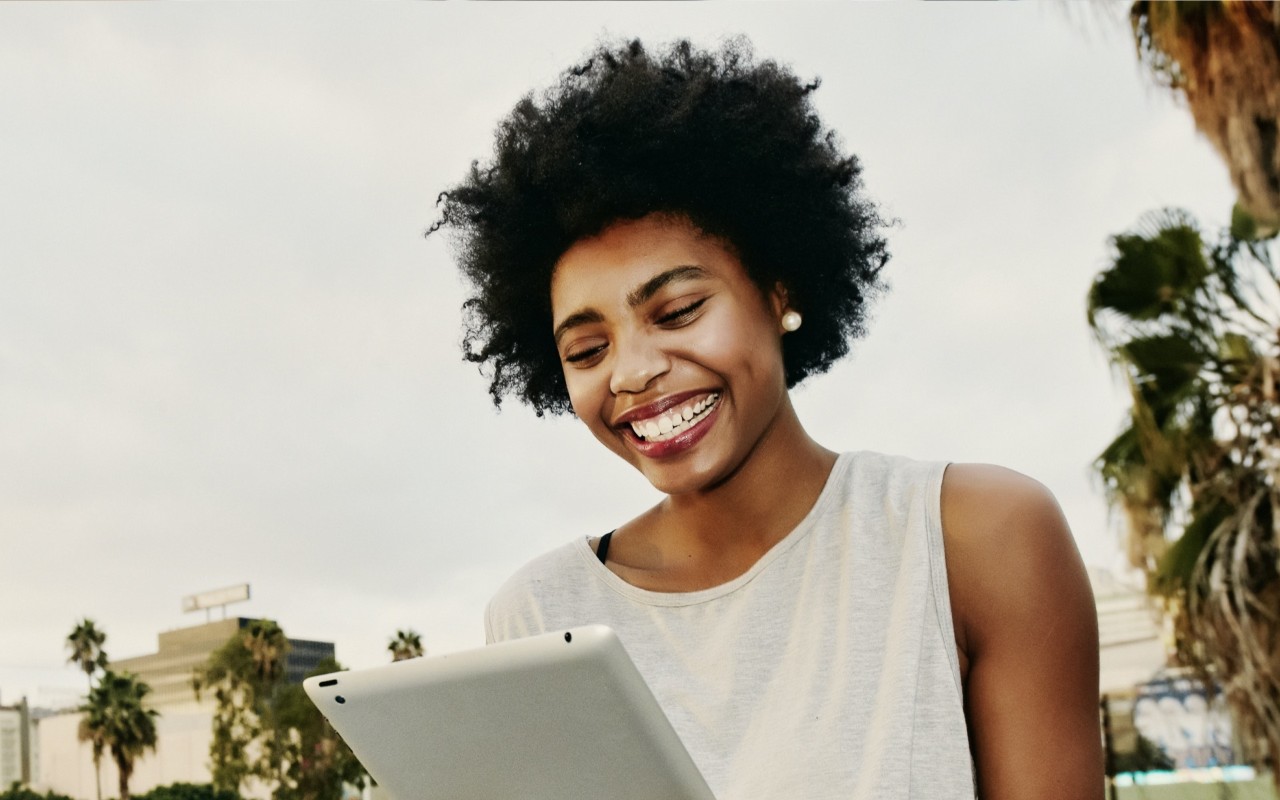 A woman is smiling while signing up for e-delivery on her tablet.