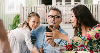 A woman shares her phone screen with a man and small child.