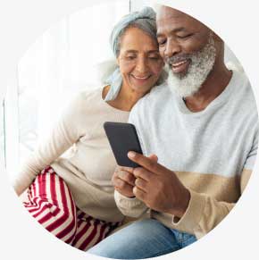 Mature couple smiles as they look at something on a phone together.