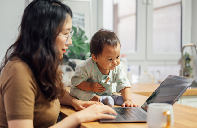 A mother and her baby are looking at a laptop screen.