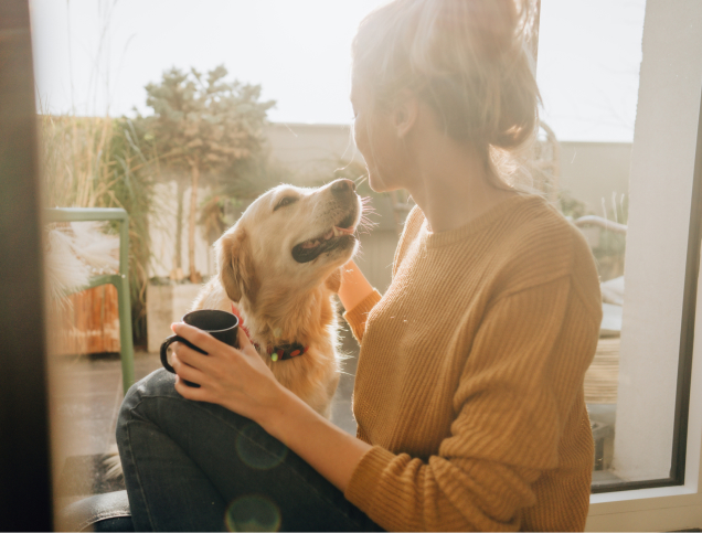 Woman looking at dog while holding a coffee mug