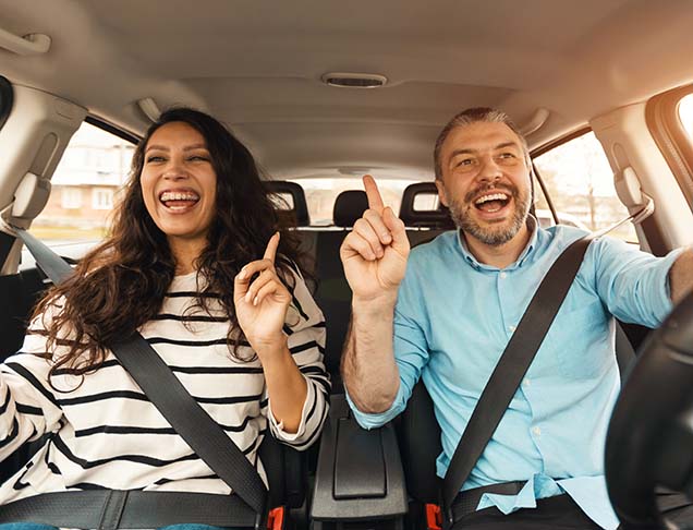 A man and woman are happily riding in a car.
