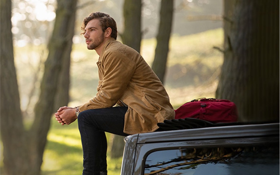 A young man is sitting in the woods on the roof his car contemplating incorporating ESG investing into his portfolio.