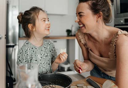 Woman smiling with her daughter while baking.