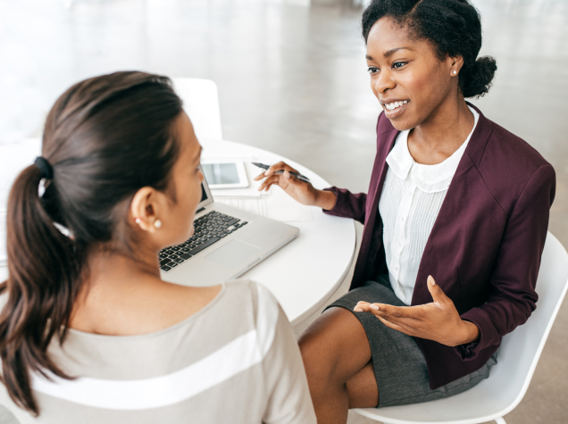  Two women are facing each other in a conversational way.