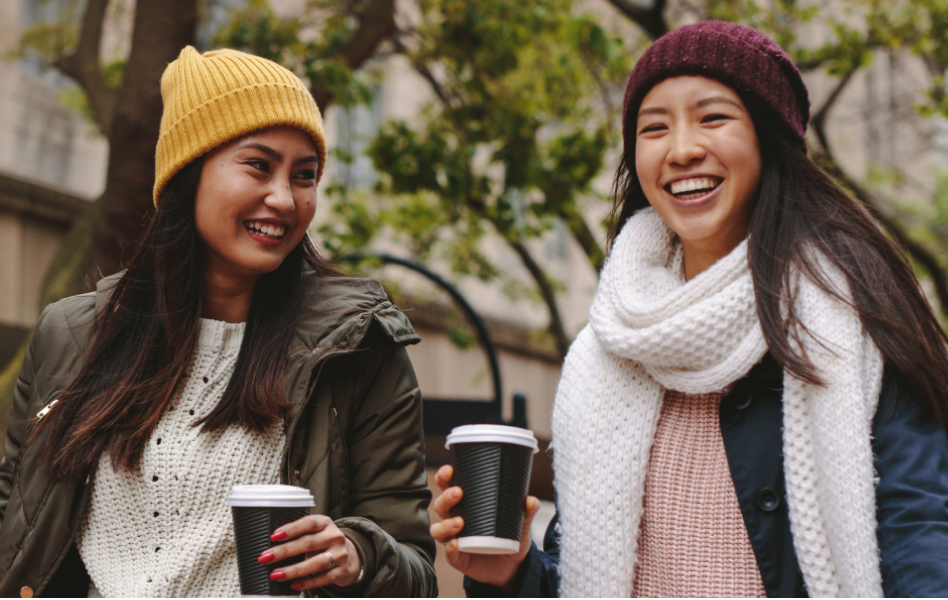 A young woman in a hat and scarf is accompanied by a smiling woman.