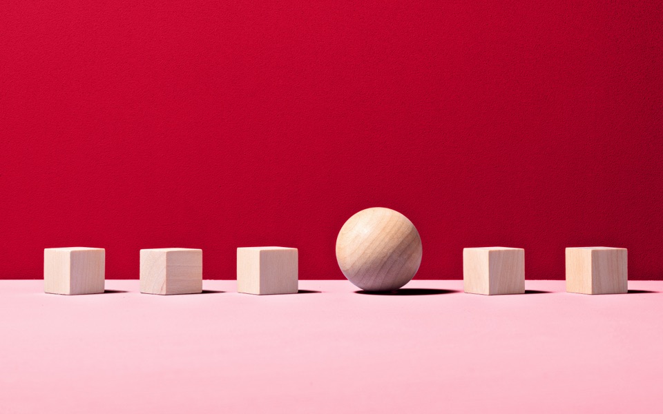 A wooden sphere sits between 5 wooden cubes.