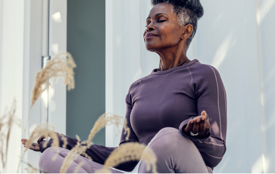 An older woman is meditating outside.
