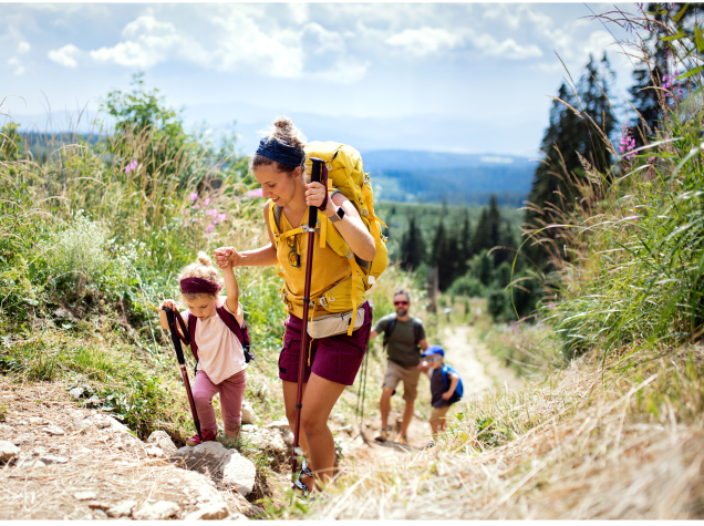  A woman is helping a child up a rocky surface during a hike.