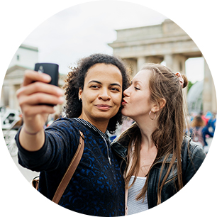 A woman kisses her partner's cheek for a selfie.