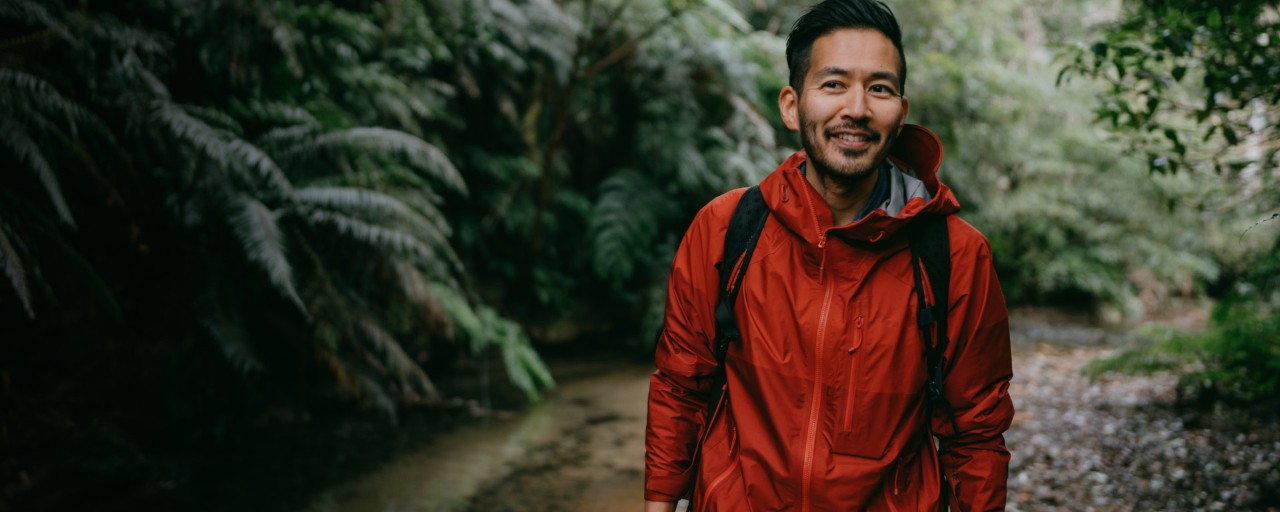 A person in a red jacket goes for a walk in the woods.