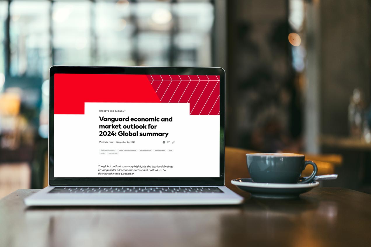 A picture of a laptop open to the Vanguard's economic and market outlook for 2024 Global economy article. A coffee cup on a saucer is next to the laptop.