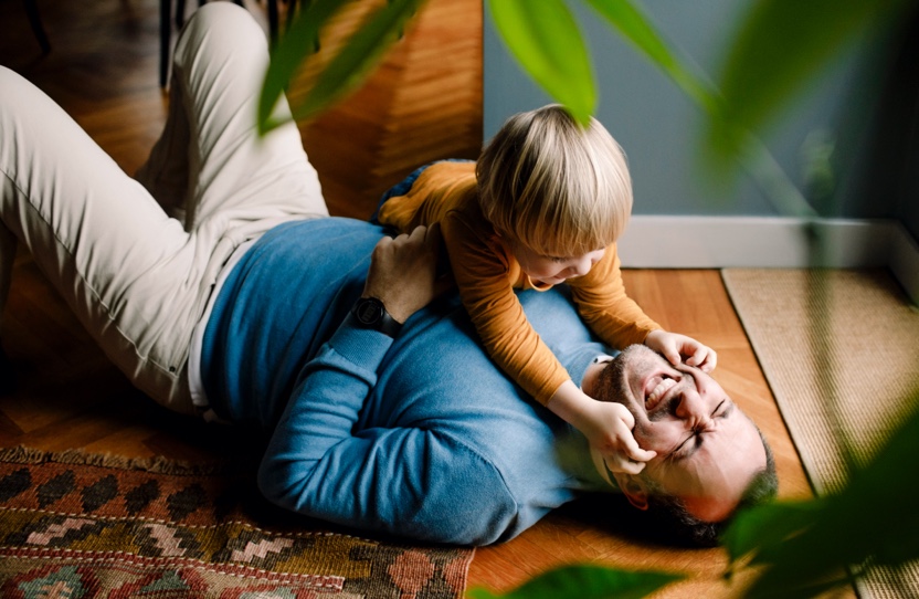 A man is laughing and holding his son.