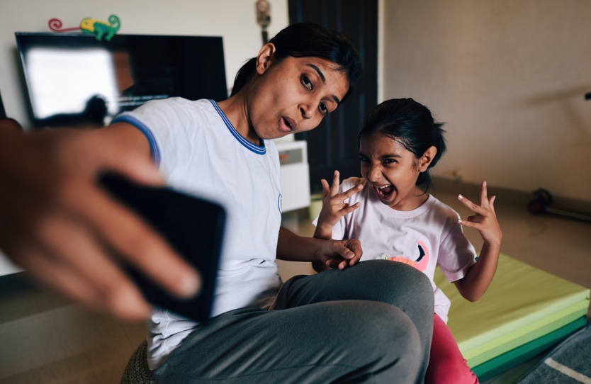 A mother is taking a silly selfie with her daughter.