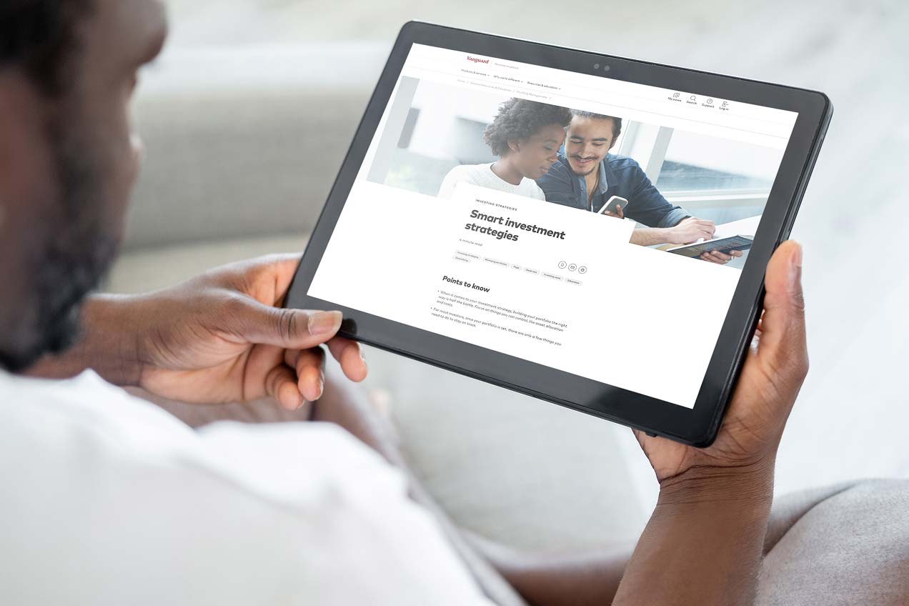 A person holds a tablet displaying a webpage titled "Smart investment strategies." The webpage features an image of a smiling couple reviewing documents together.