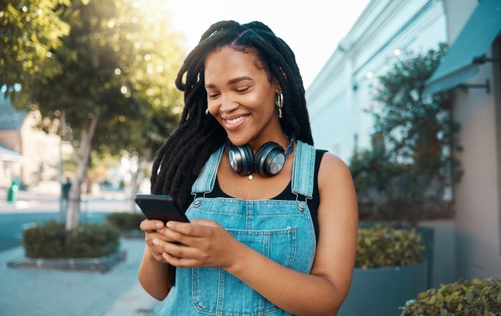 Woman in overalls smiling at her phone 
