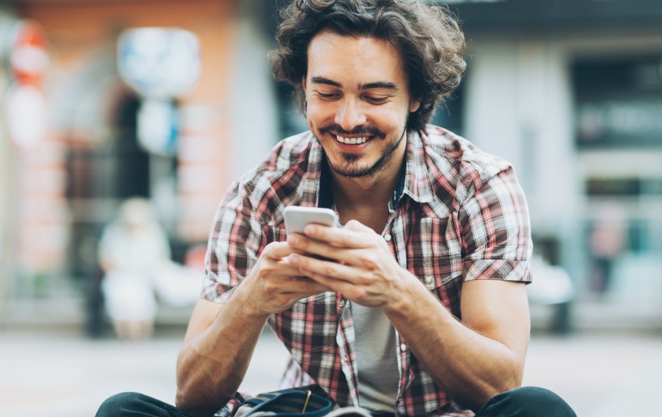 A man smiles as he looks at his phone.