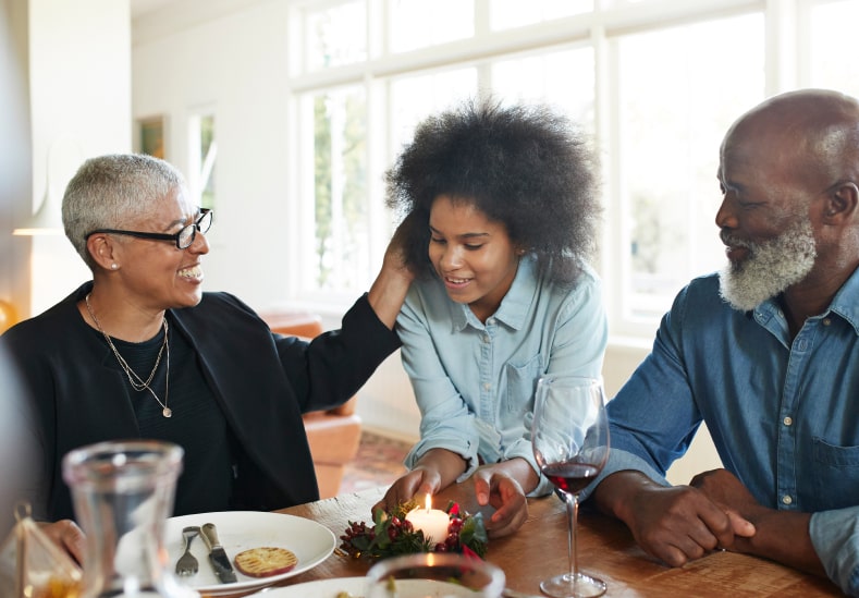 Three people smiling sitting at the kitchen table.
