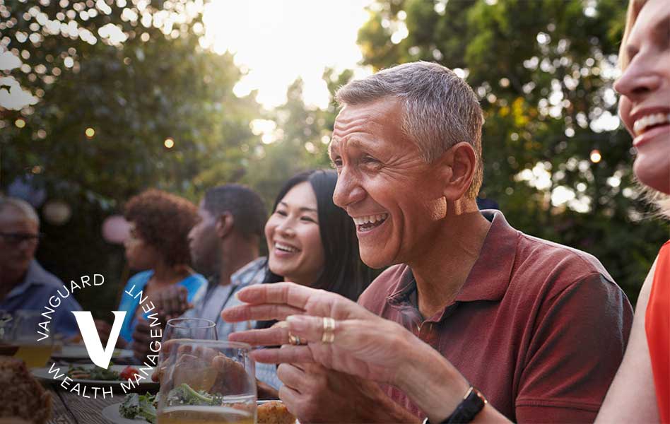 Man laughing with friends and family at an outdoor dinner party