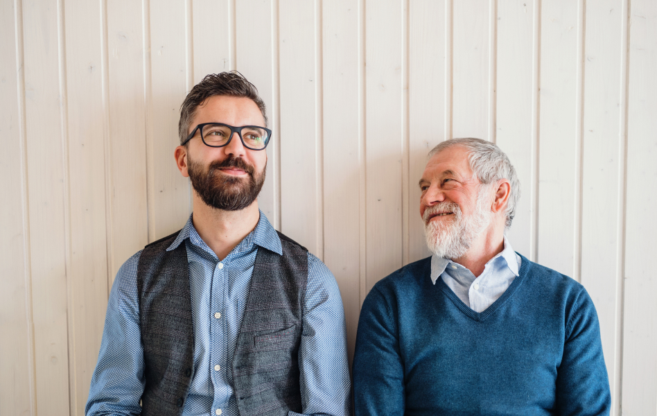 Older man smiling at his adult son.