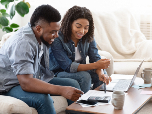 Two people smiling while looking at documents on table.